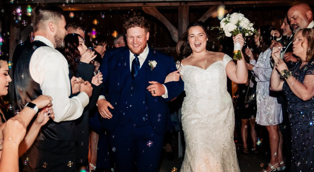 Wedding couple walking down stairs with guests celebrating.